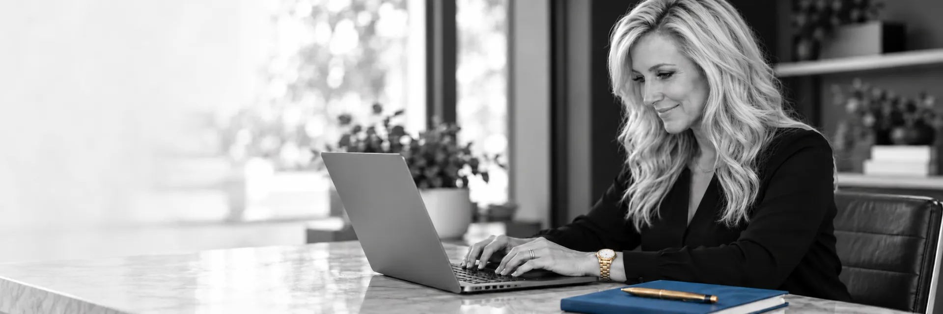 Julie Fisher, fractional CMO, working at a laptop with blue and brass desk accents